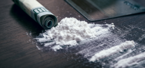 cocaine, one of the most common street drugs, in powder form on a table with a rolled hundred dollar bill