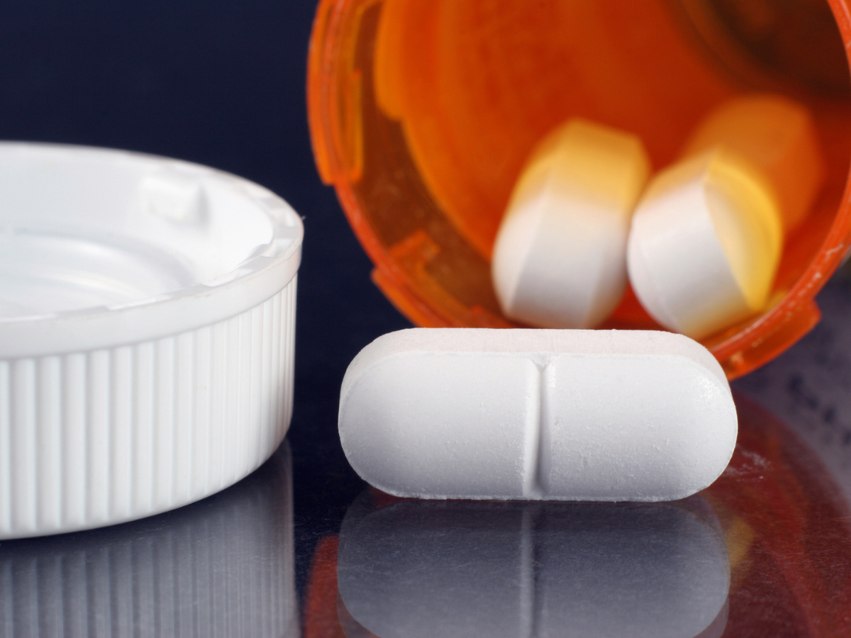 Pills spilling out a prescription bottle from someone who needs rehab for opioid addiction